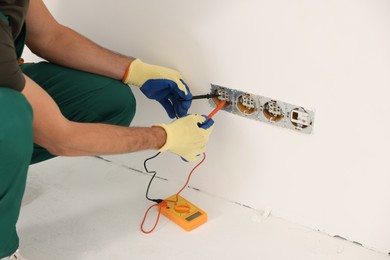 Photo of Electrician with tester checking voltage indoors, closeup