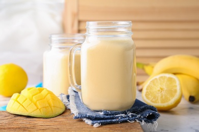 Photo of Mason jars with healthy detox smoothie and ingredients on table