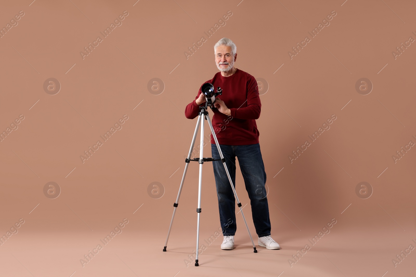 Photo of Senior astronomer with telescope on brown background
