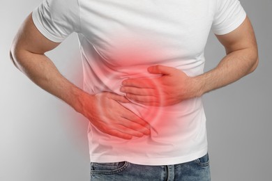 Man suffering from pain in lower right abdomen on light grey background, closeup. Acute appendicitis
