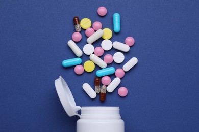 Photo of Bottle and antidepressant pills on dark blue background, flat lay