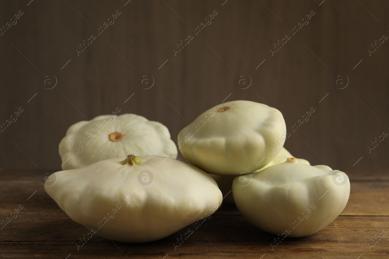 Photo of Fresh ripe pattypan squashes on wooden table