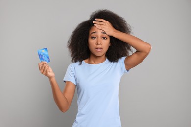 Photo of Confused woman with credit card on grey background. Debt problem
