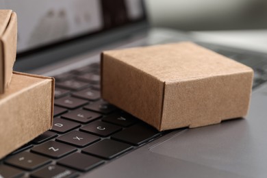 Photo of Online store. Small boxes on laptop, closeup