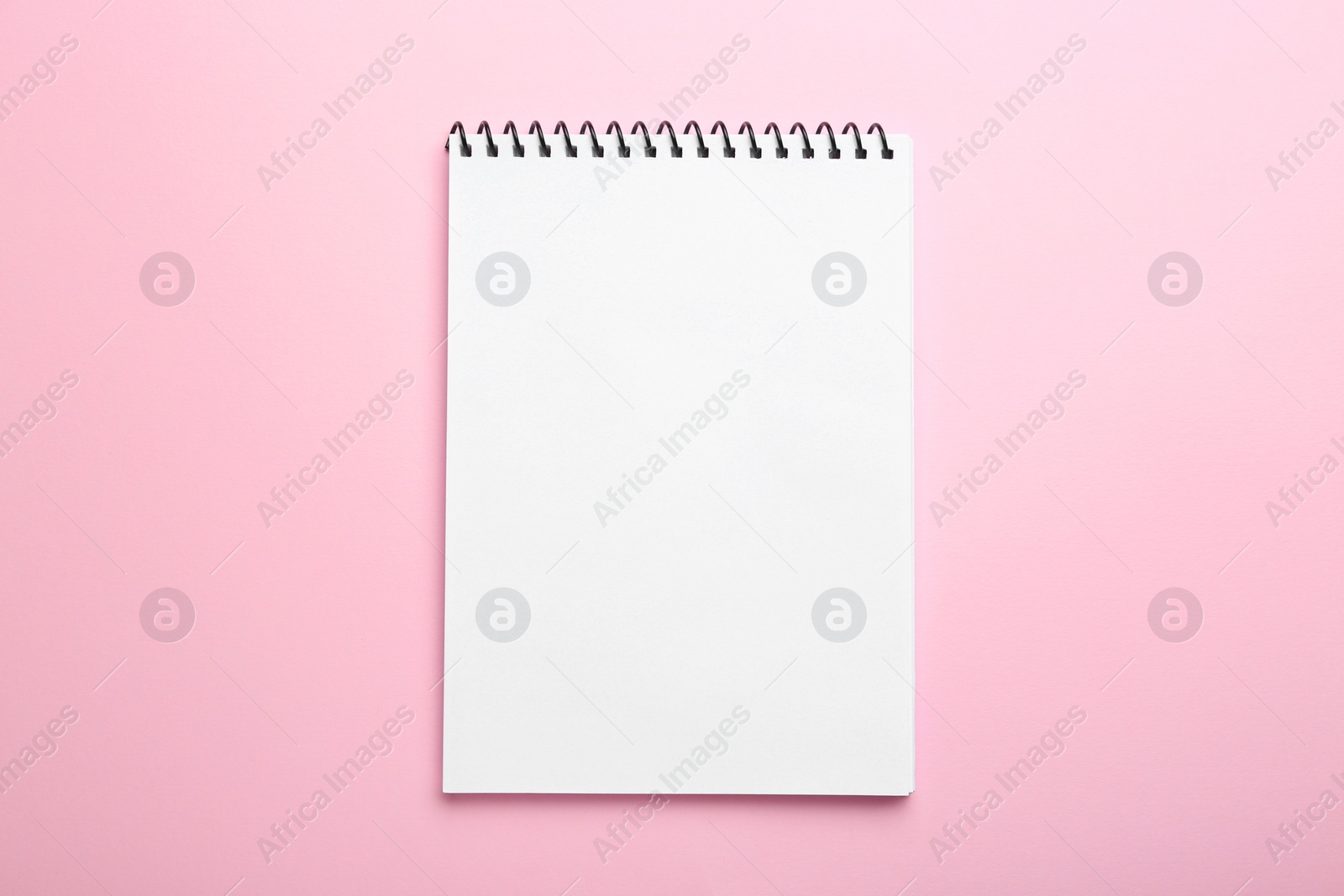 Photo of One notebook on pink background, top view. Space for text