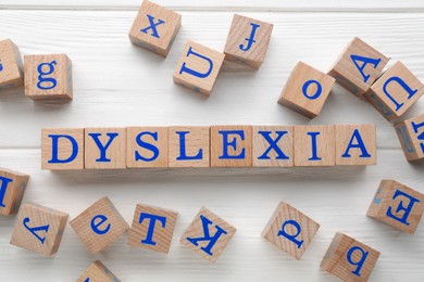 Photo of Cubes with word Dyslexia on white wooden table, flat lay