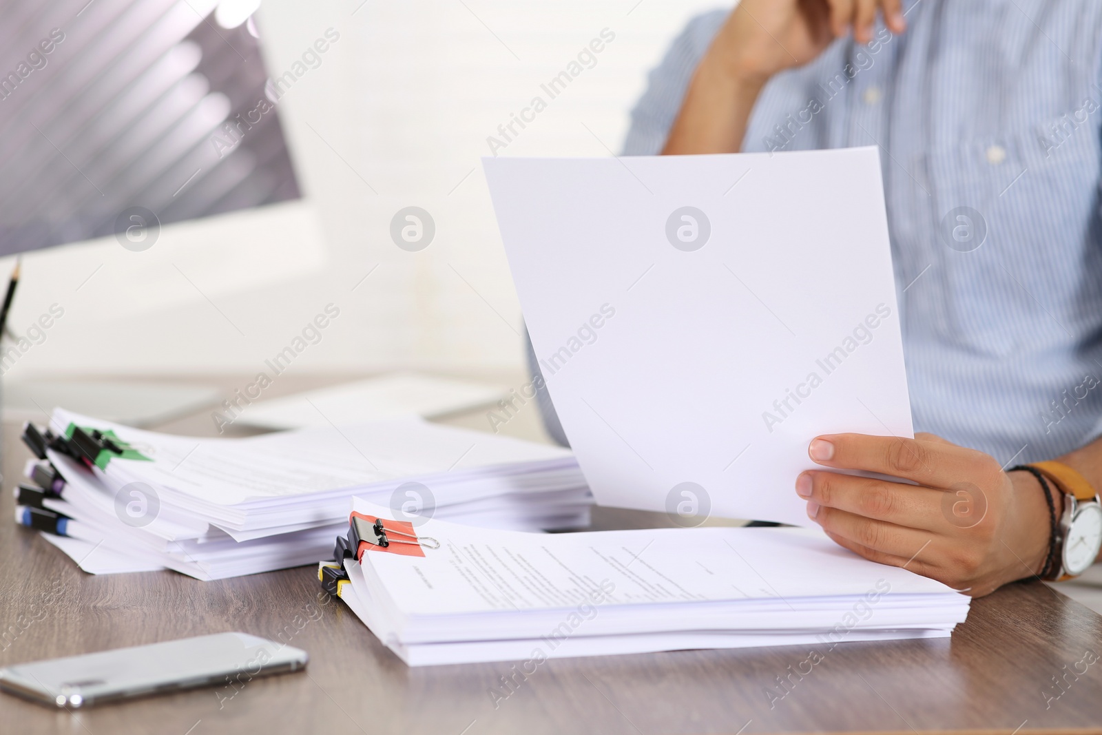 Photo of Man working with documents at wooden table in office, closeup