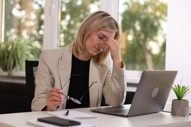 Photo of Overwhelmed woman sitting at table in office