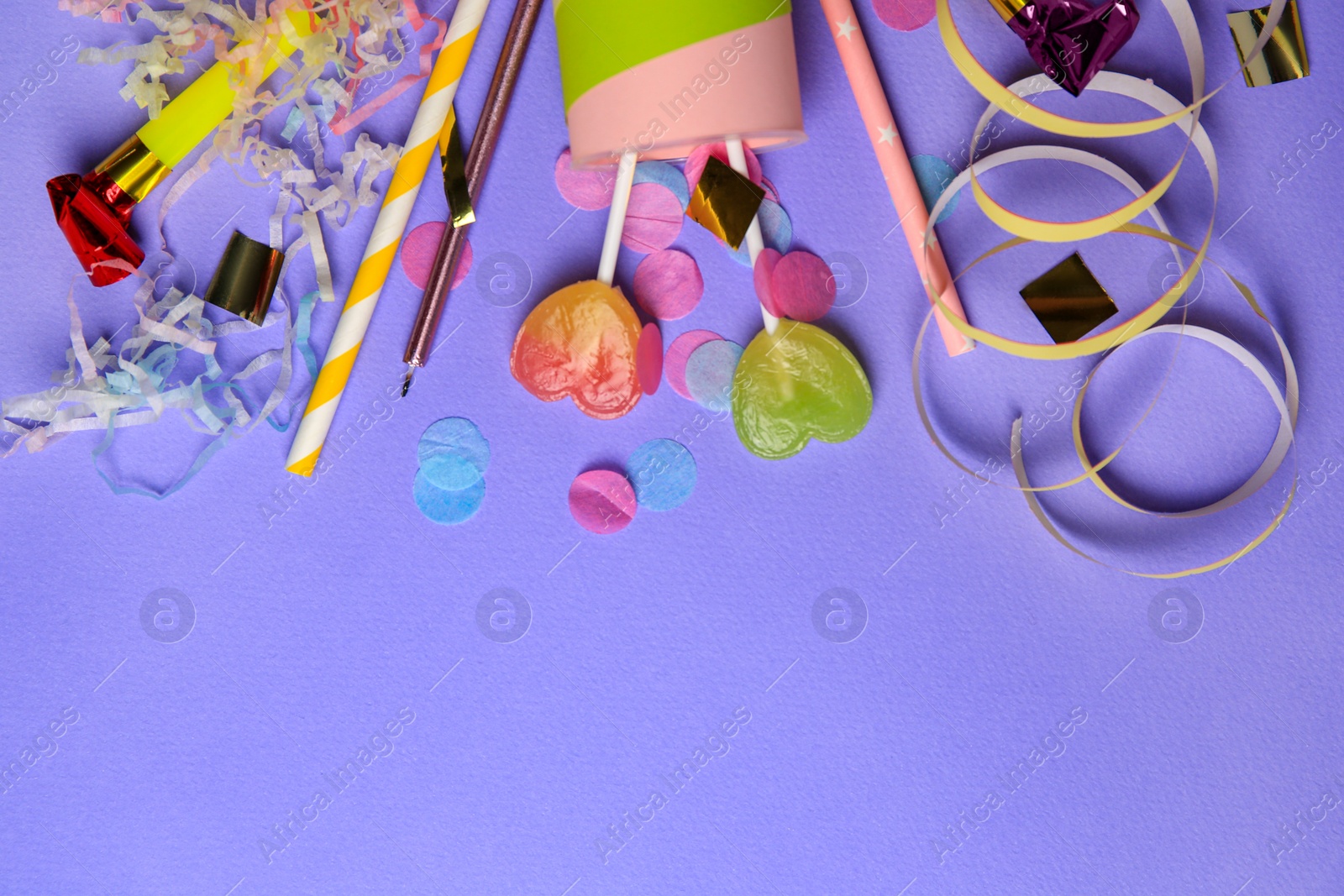 Photo of Party popper, lollipops and festive decor on violet background, flat lay