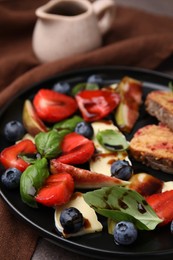 Delicious salad with brie cheese, berries and balsamic vinegar on table, closeup