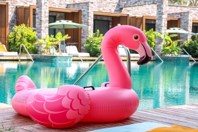 Photo of Float in shape of flamingo on wooden deck near swimming pool at luxury resort