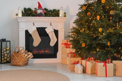 Photo of Many different gift boxes under Christmas tree and festive decor in living room