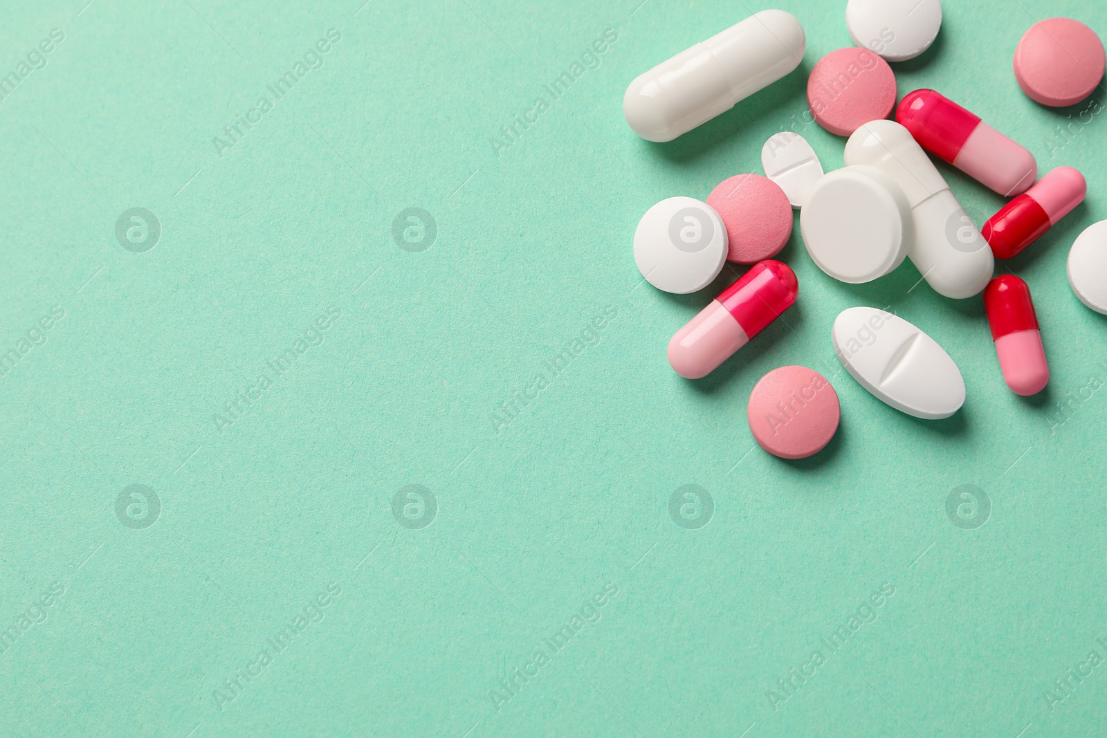 Photo of Pile of different pills on green background, flat lay. Space for text
