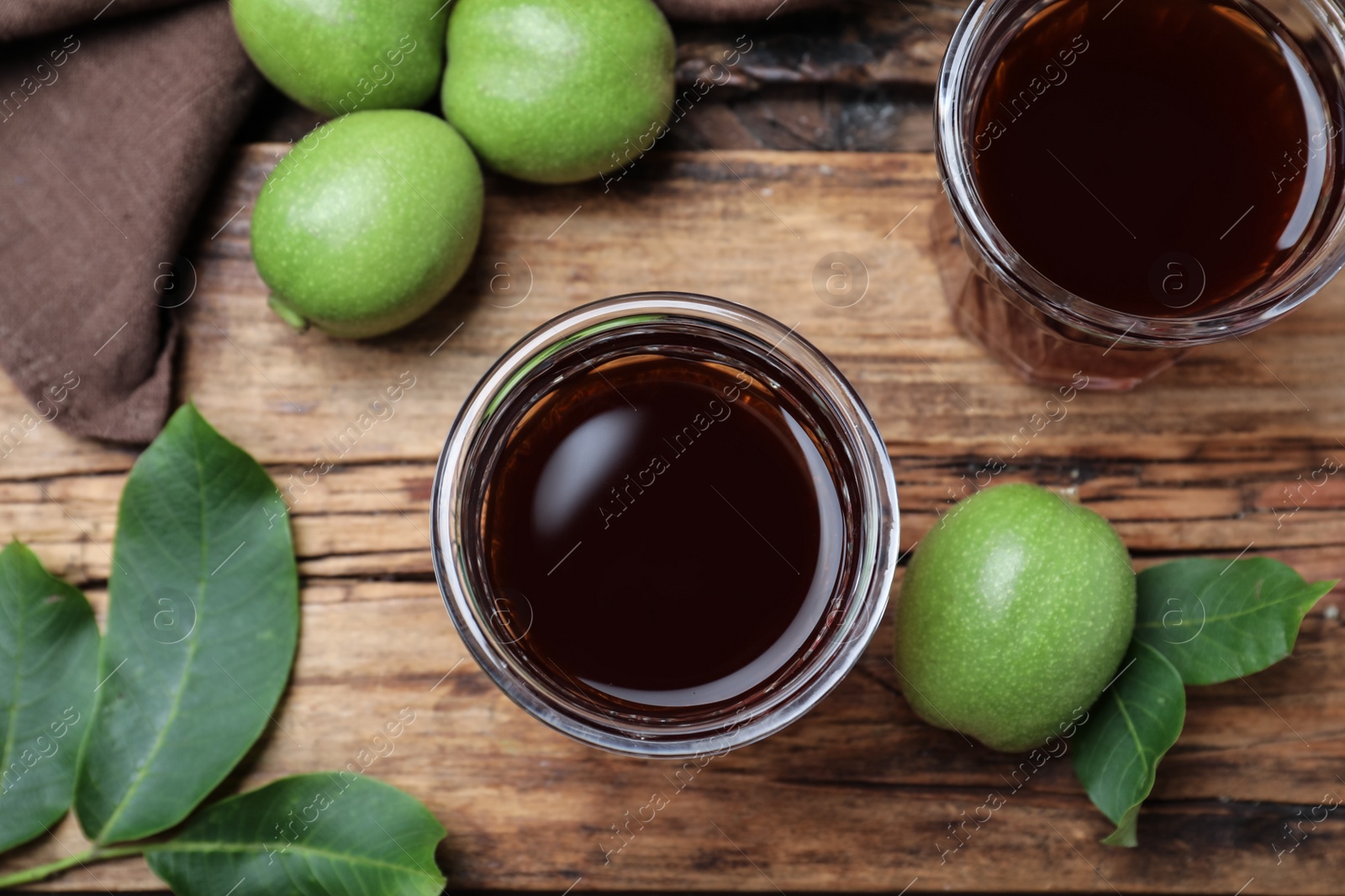 Photo of Delicious liqueur and green walnuts on wooden table, flat lay