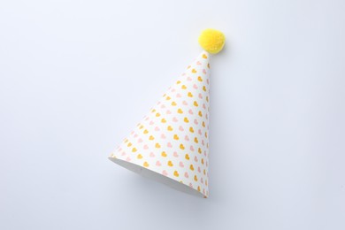 Photo of One party hat with hearts on light background, top view