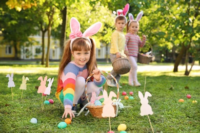 Photo of Cute little children hunting eggs in park. Easter tradition