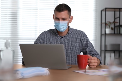 Photo of Worker with mask in office. Protective measure during COVID-19 pandemic
