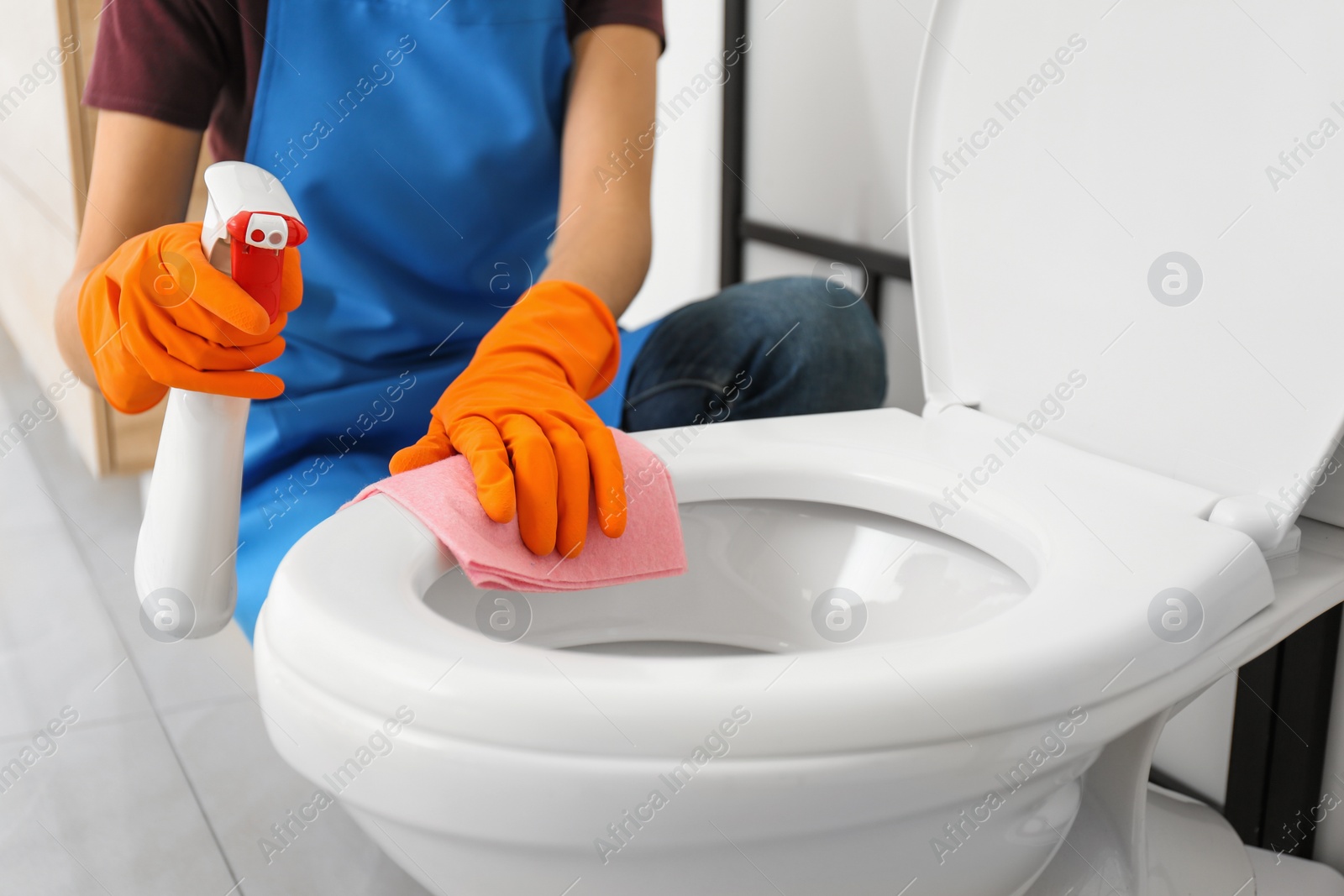 Photo of Woman cleaning toilet bowl in bathroom, closeup