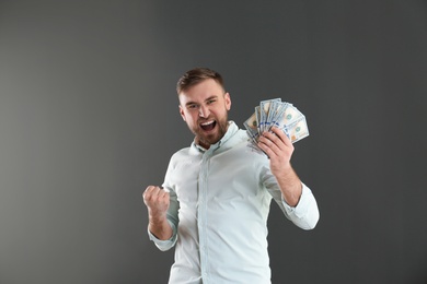 Photo of Portrait of emotional young man with money on grey background