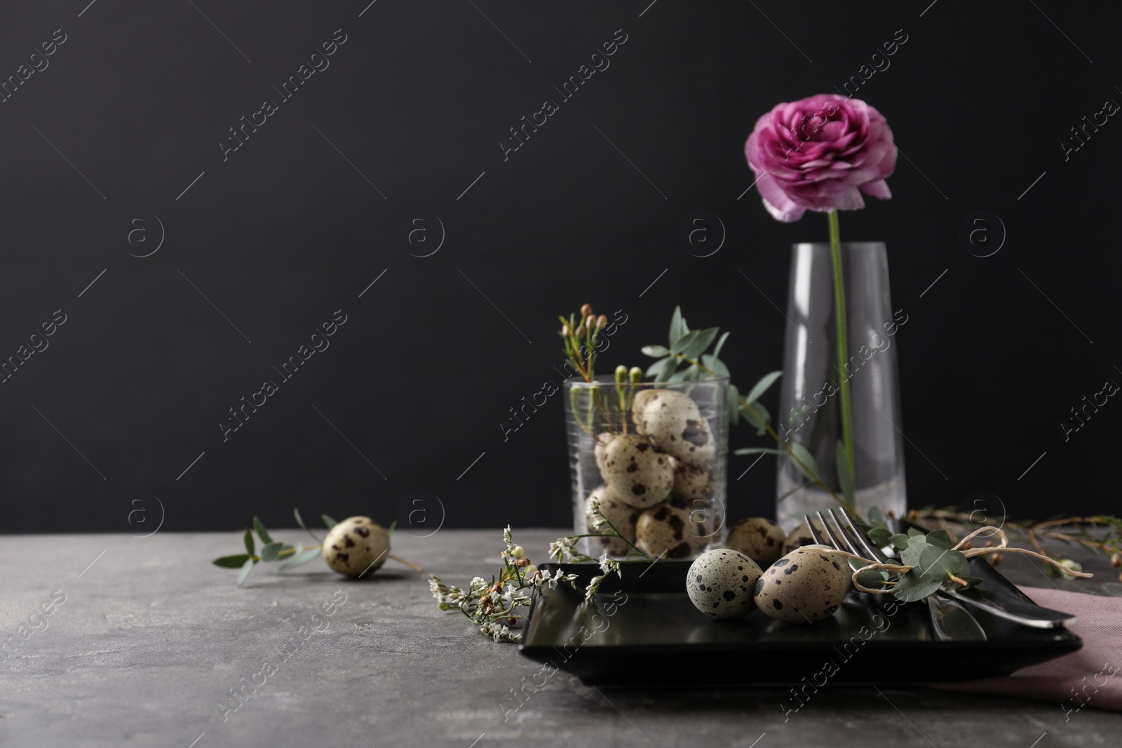 Photo of Festive Easter table setting with quail eggs and floral decoration on dark background. Space for text