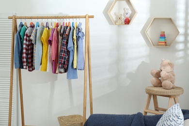 Different child's clothes hanging on rack in room