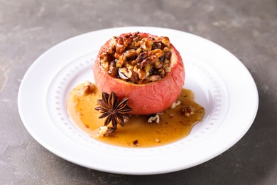 Tasty baked apple with nuts, honey and anise on gray table