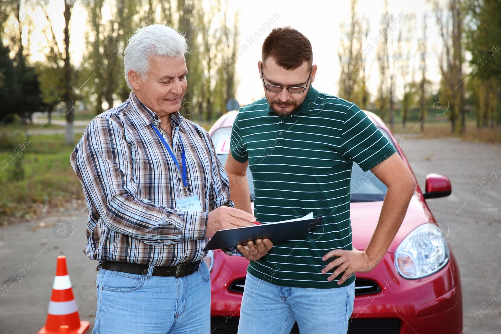 Photo of Senior instructor with clipboard and man outdoors. Get driving license