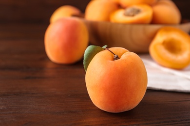 Photo of Delicious ripe sweet apricot on wooden table, closeup. Space for text