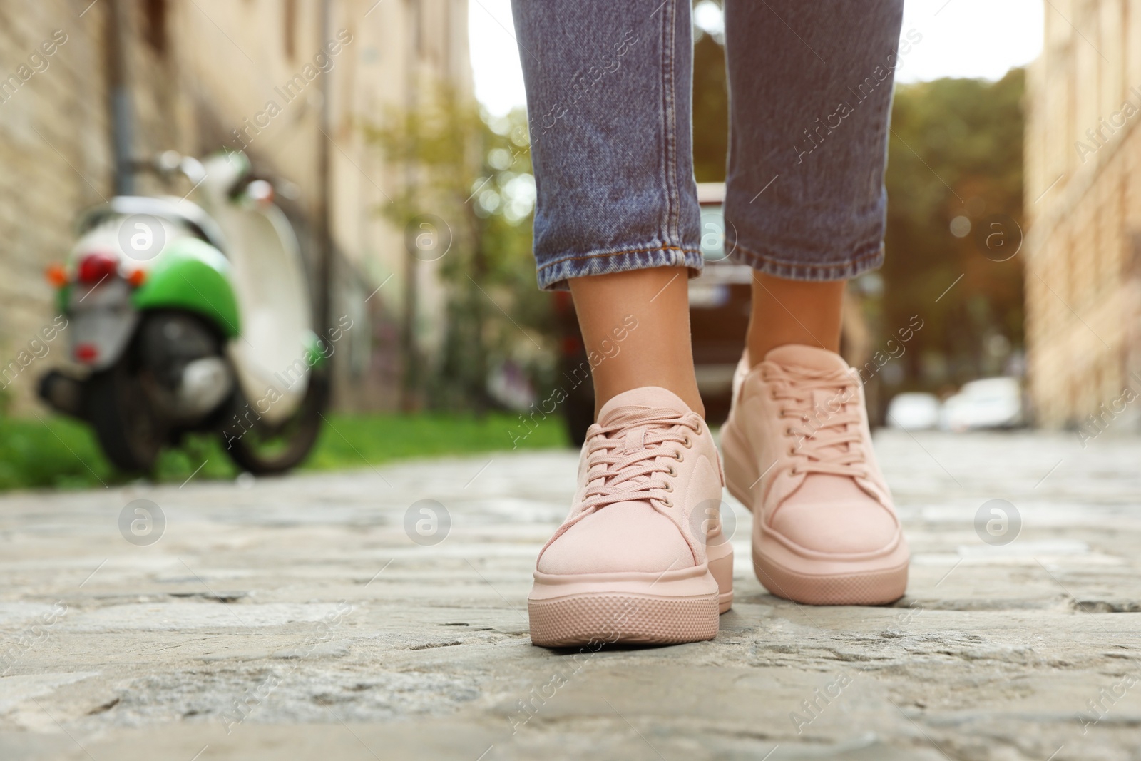 Photo of Woman in stylish sneakers walking on city street, closeup