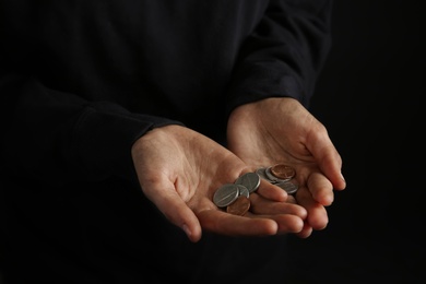 Poor woman holding coins on dark background, closeup