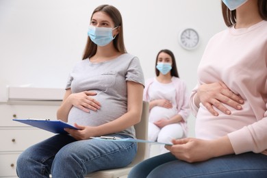 Photo of Group of pregnant women in protective masks at courses for expectant mothers indoors, closeup