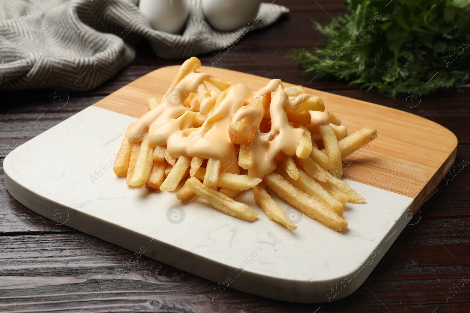 Photo of Delicious french fries with cheese sauce on wooden table