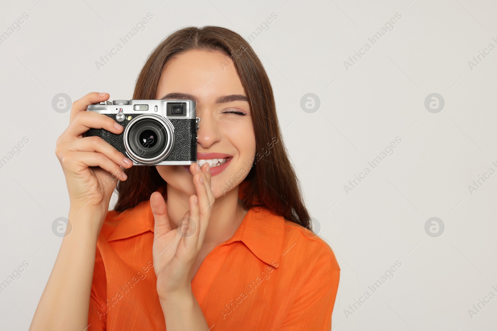 Photo of Young woman with camera taking photo on white background, space for text. Interesting hobby