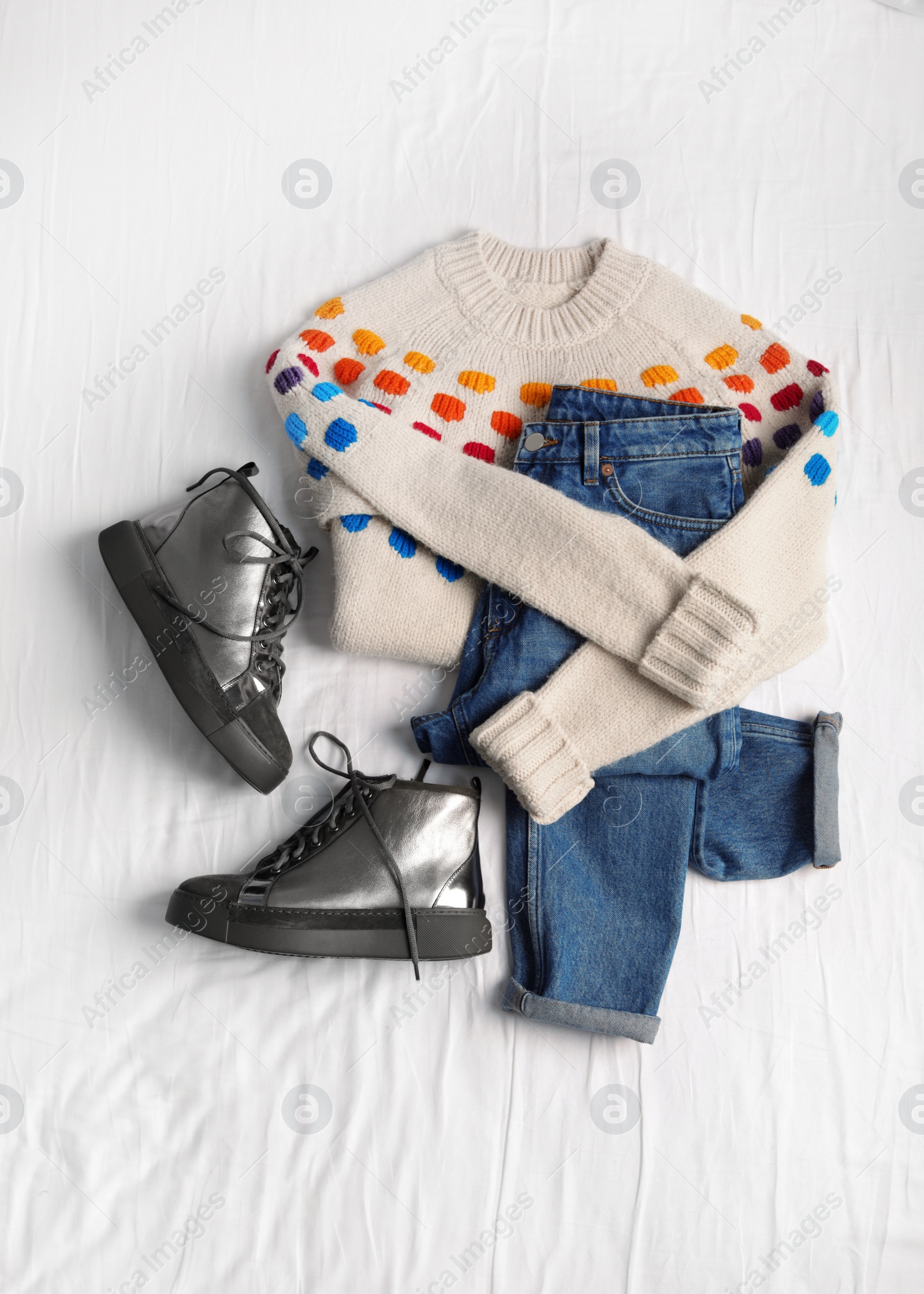 Photo of Flat lay composition with jeans, sweater and shoes on white fabric