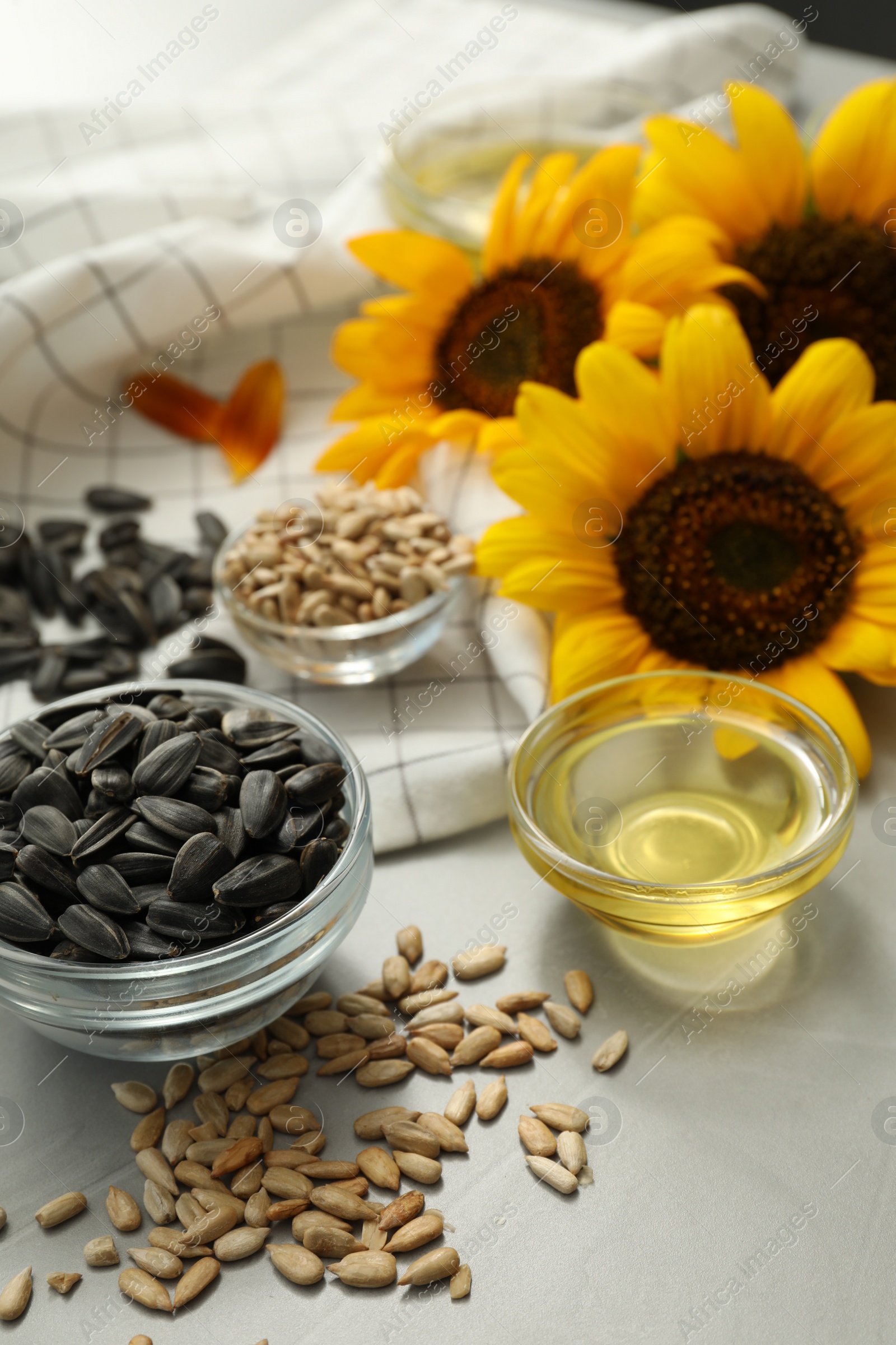 Photo of Sunflower oil and seeds on grey table, closeup