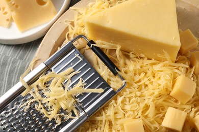 Photo of Grated, whole pieces of cheese and grater on table, top view