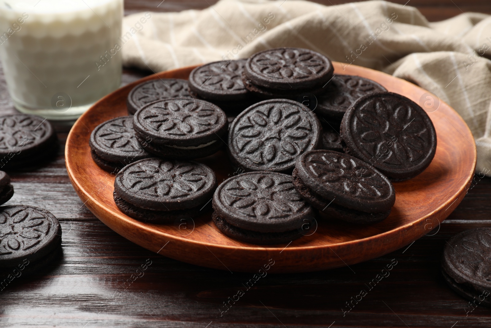 Photo of Plate with tasty sandwich cookies on wooden table, closeup