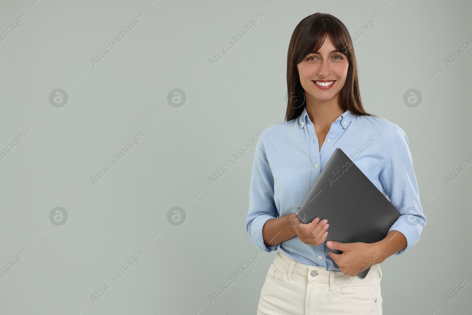 Photo of Happy secretary with laptop on light grey background. Space for text