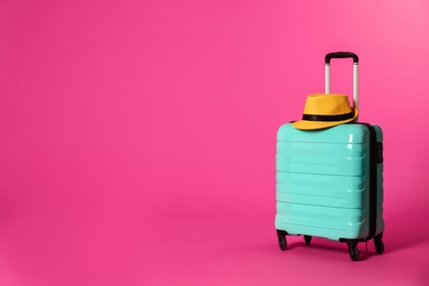 Photo of Stylish suitcase with hat on color background. Space for text