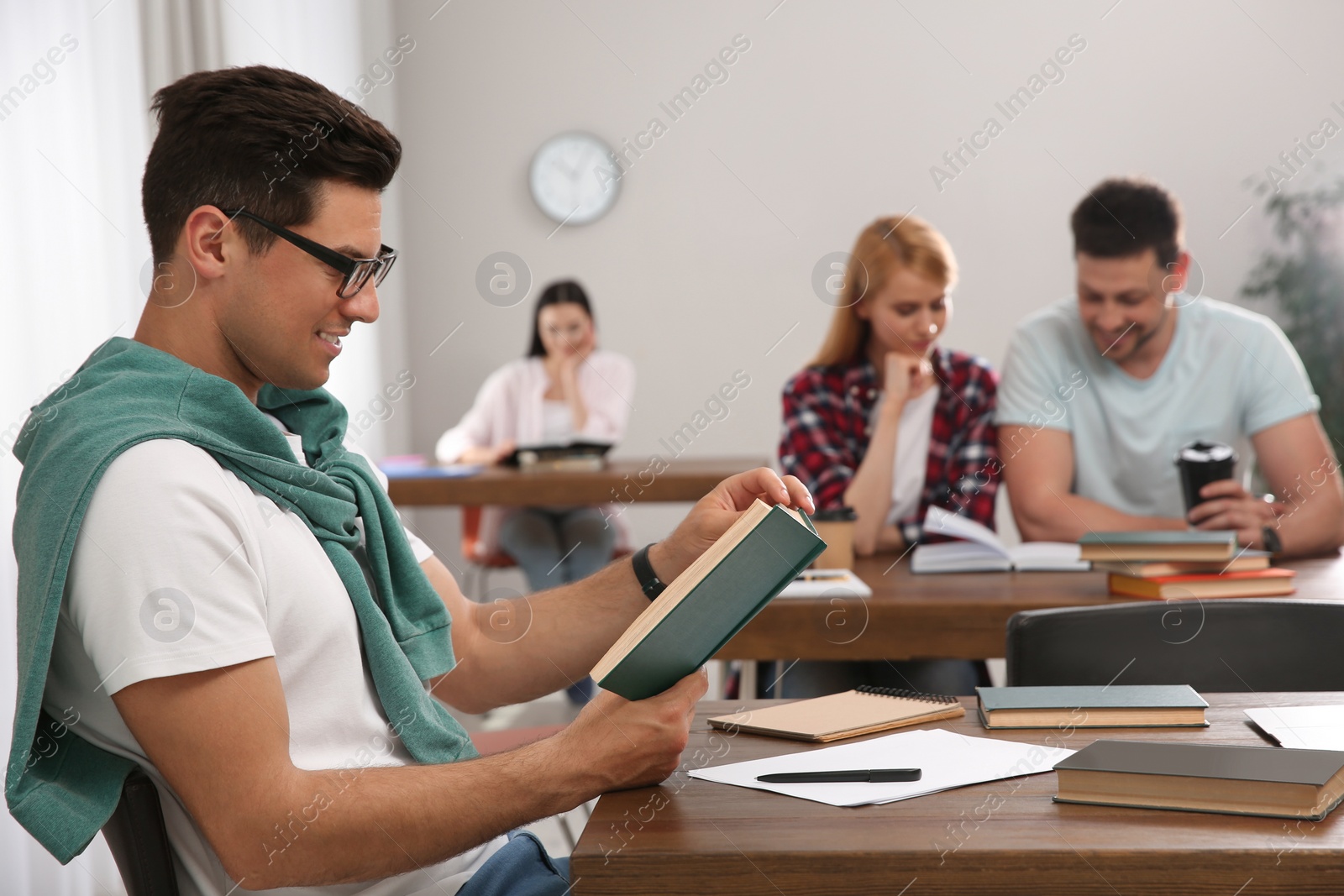 Photo of Man reading book at table in library