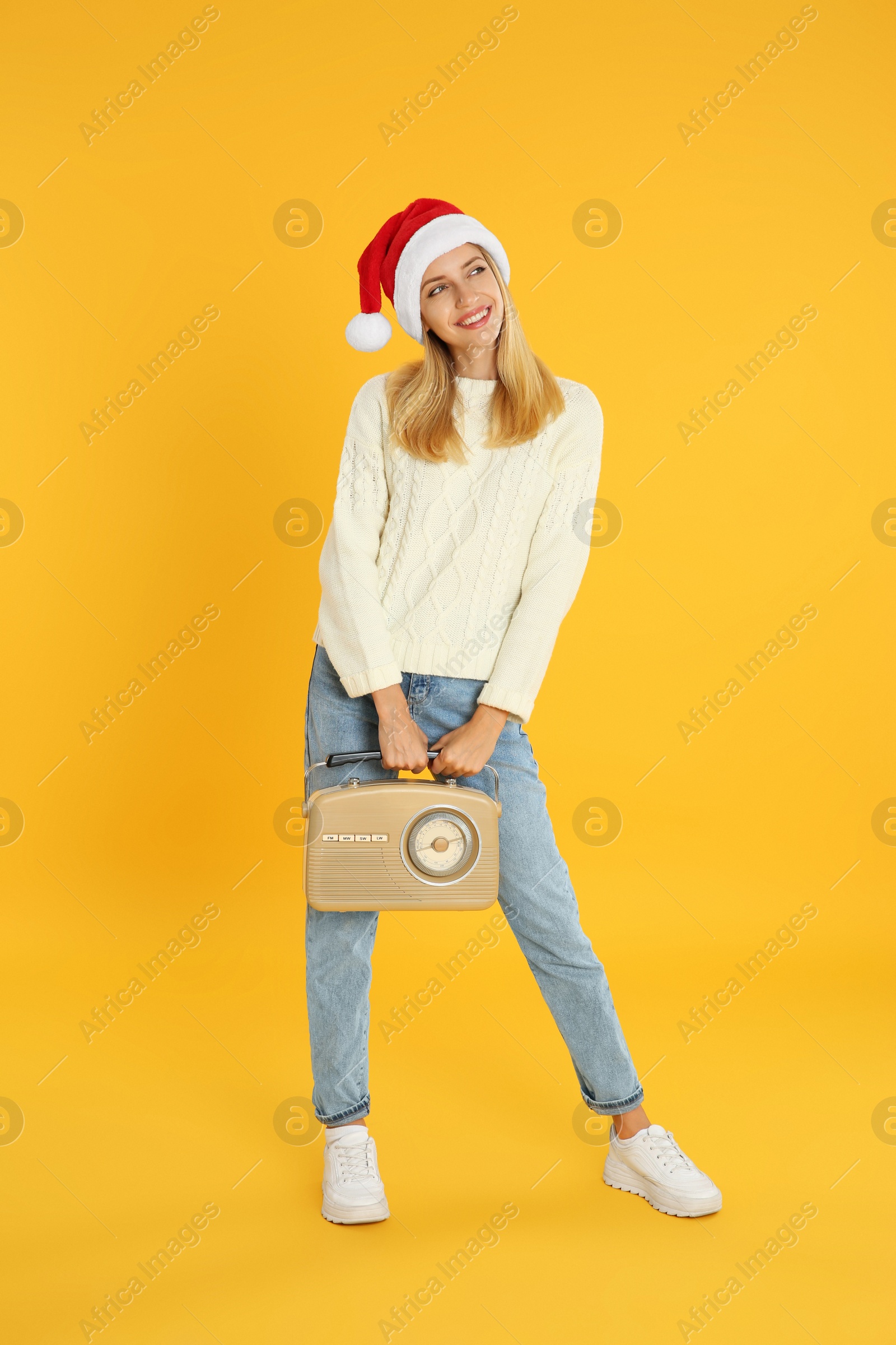 Photo of Happy woman with vintage radio on yellow background. Christmas music