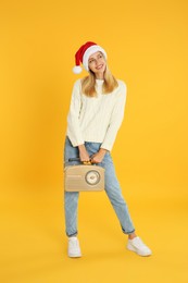 Happy woman with vintage radio on yellow background. Christmas music