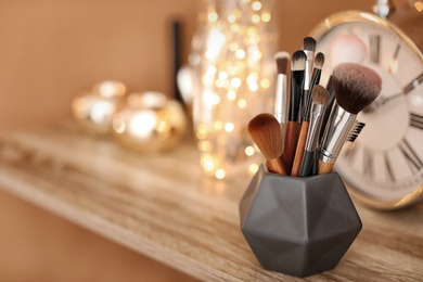 Holder with makeup brushes on table