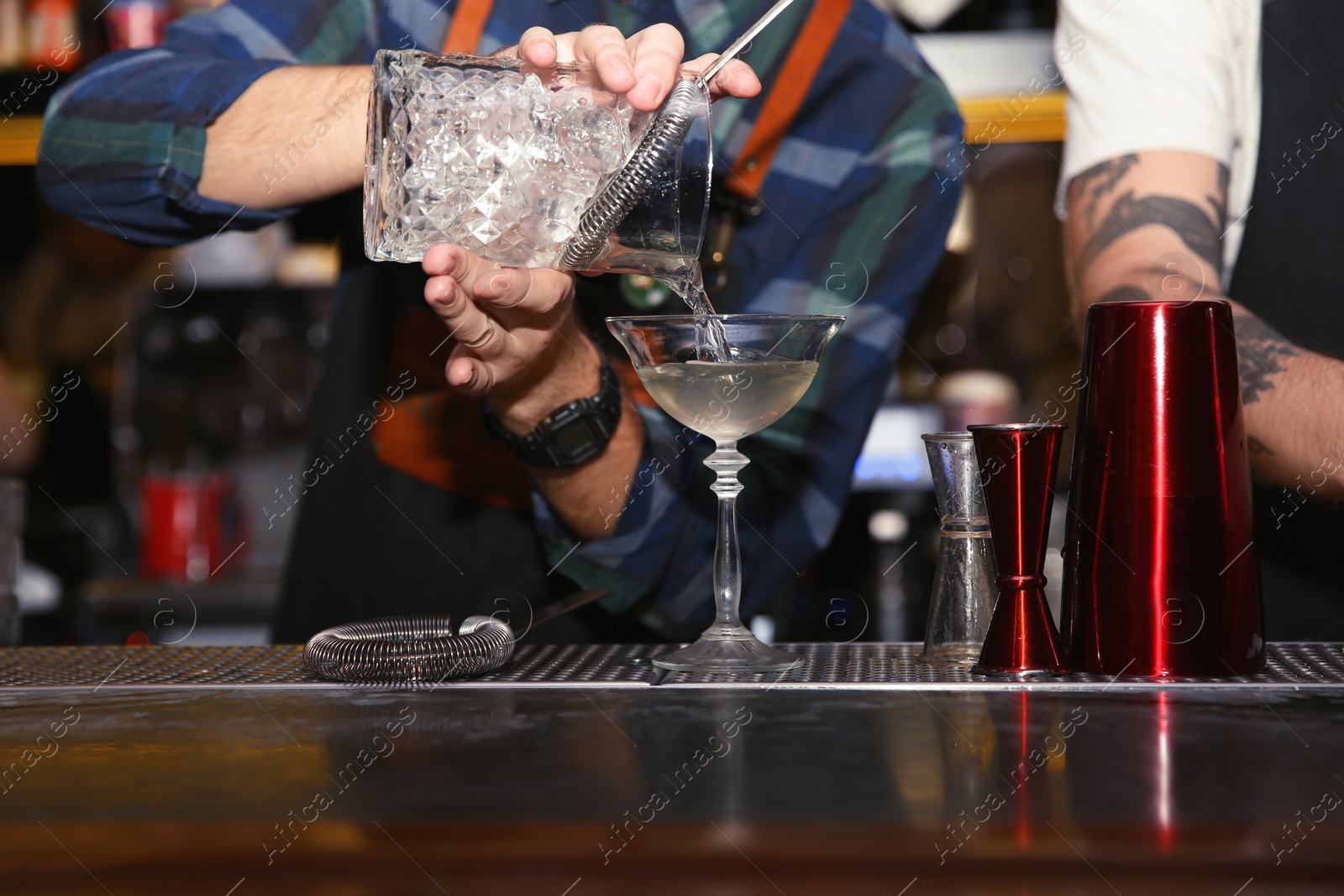 Photo of Bartender pouring tasty cocktail at counter in nightclub, closeup