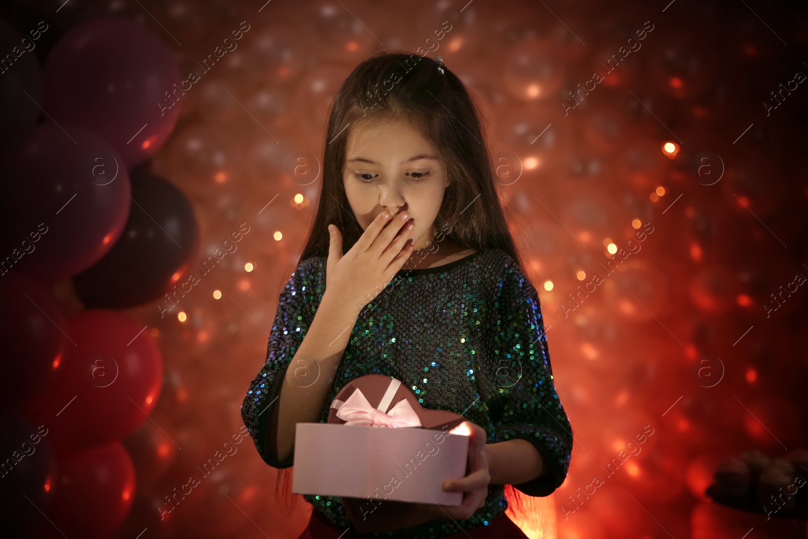 Photo of Happy little girl with gift in beautifully decorated room at home. Birthday celebration