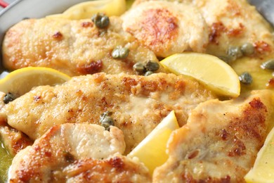 Photo of Delicious chicken piccata with lemons as background, closeup