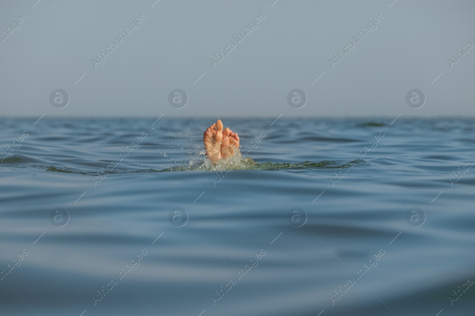 Photo of Drowning woman's feet sticking out of sea