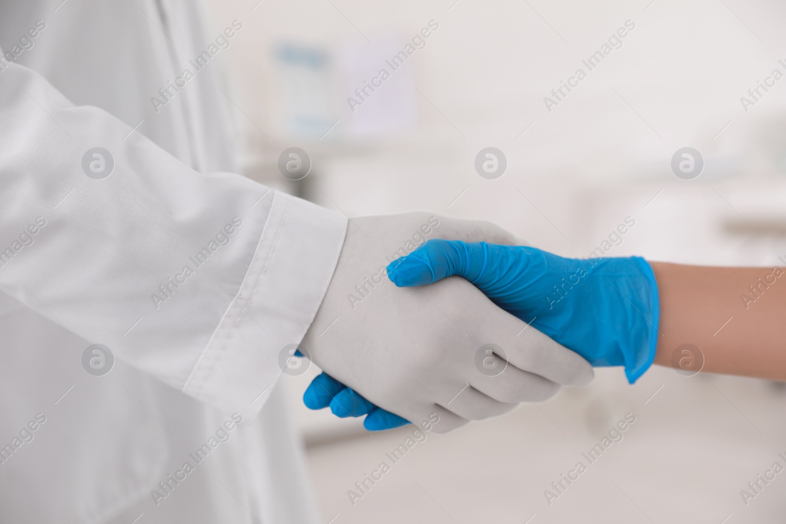 Photo of Doctors in medical gloves giving handshake at hospital, closeup