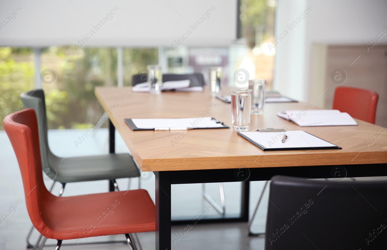 Photo of Clipboards and glasses of water on wooden table in modern office