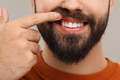 Photo of Man showing his clean teeth on gray background, closeup